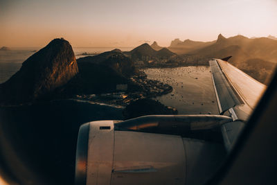 Airplane in mountains against sky during sunset