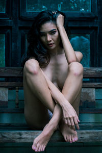 Naked young woman sitting on bench