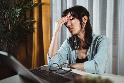 Frustrated young woman by laptop in office