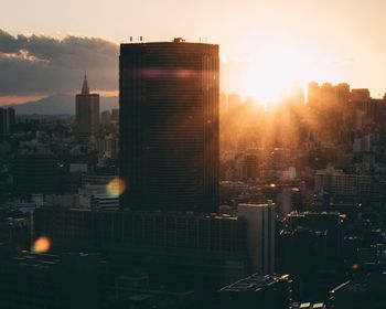 Modern buildings in city against sky during sunset