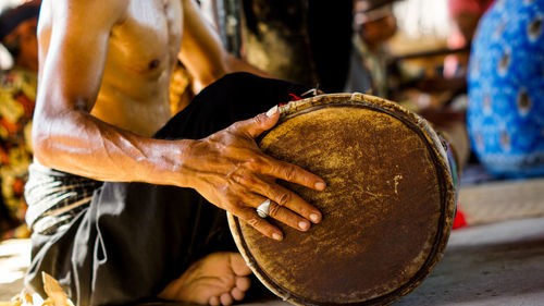 Midsection of man playing drum