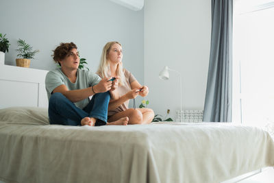 Female friends sitting on bed at home