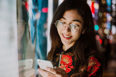 Portrait of smiling young woman using smart phone outdoors