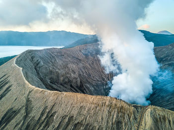 Smoke emitting from volcanic mountain against sky