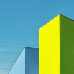 Low angle view of yellow building against blue sky