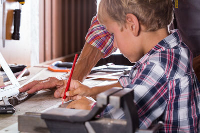 Midsection of carpenter teaching kid