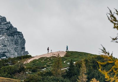 A couple of hikers standing on top of hill in mountains.