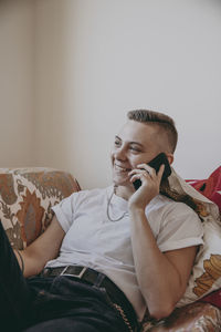 Man using mobile phone while sitting on sofa at home