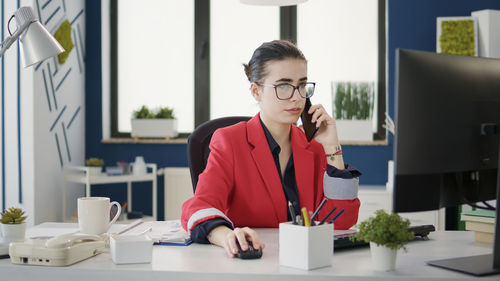 Businesswoman talking on smart phone at desk