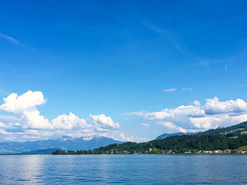 Scenic view of sea and mountains against blue sky