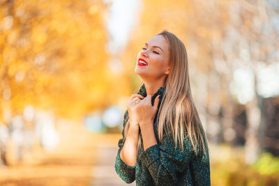 Beautiful young woman standing by autumn leaves