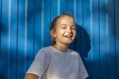 Unbridled joy, girl's laughter echoes against the outdoor blue wall