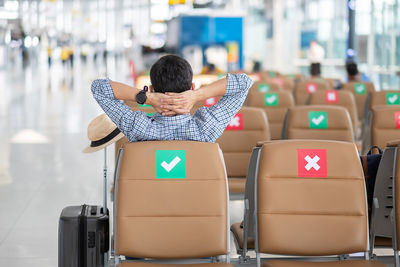 Rear view of boy sitting on chair at airport