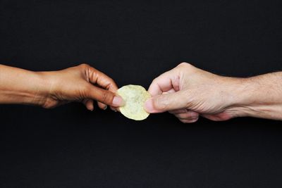 Close-up of man holding hands over black background