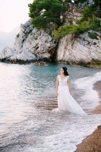 Woman standing on rock by sea