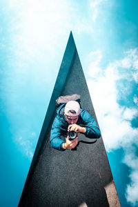 Photographer framed in a triangular mirror against a clear blue sky. ideal for artistic projects.