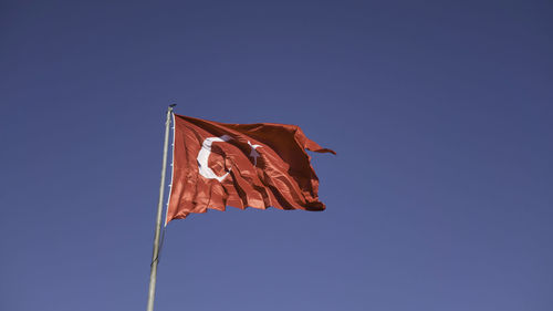 Low angle view of flag against clear blue sky