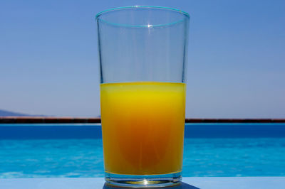 Close-up of orange juice on table against sea