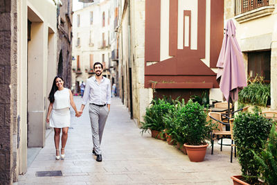 Portrait of happy couple holding hands and walking on city street