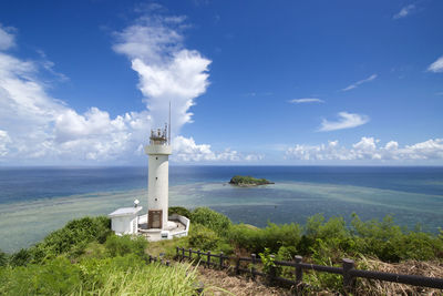 Lighthouse by sea against sky