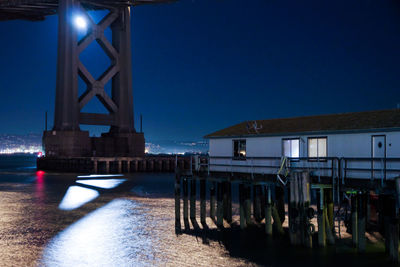 Illuminated bridge against clear sky at night