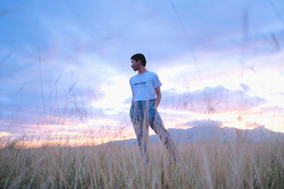 Young man standing on field against sky