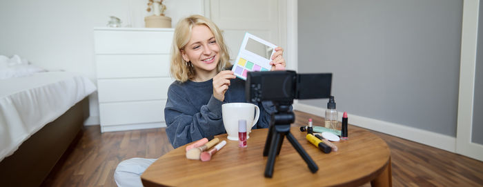 Side view of young woman sitting on table