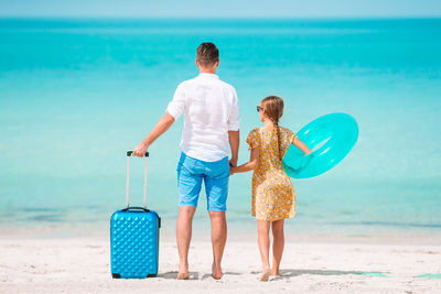 Rear view of father and daughter standing on beach