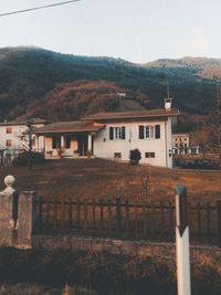 Houses by buildings in town against sky