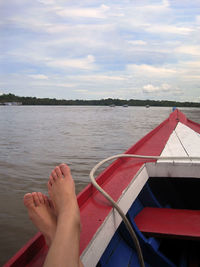 Low section of person on boat in lake against sky