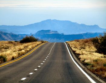 Empty road along landscape and mountains against sky