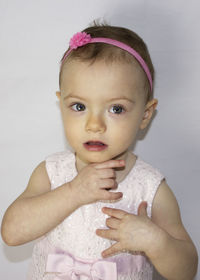 Portrait of cute baby girl standing against white background