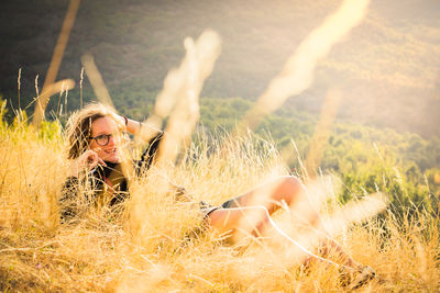 Portrait of young woman resting on field