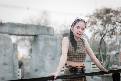 Portrait of beautiful woman standing by railing 