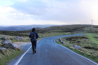 Rear view of woman walking on empty road