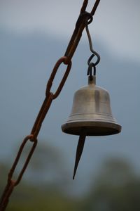 Close-up of bell hanging from metallic chain