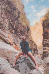 Low angle view of person sitting on rock