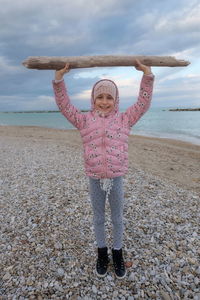 Portrait of girl holding branch at beach