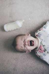 Overhead view of toddler crying while lying on floor at home