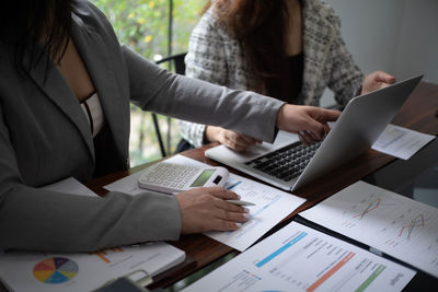 Midsection of businesswoman using laptop at office