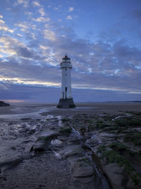 Lighthouse by sea against sky