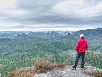 Rear view of man standing on mountain against sky