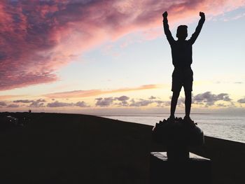 Silhouette man standing at beach against sky during sunset