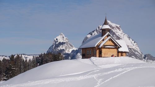 Traditional building by snowcapped mountain against sky