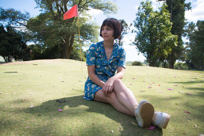 Portrait of woman sitting on grass against trees