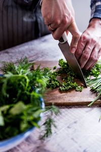 Cropped hands of man cutting vegetables on table