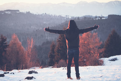 Rear view of person standing on snow covered mountain