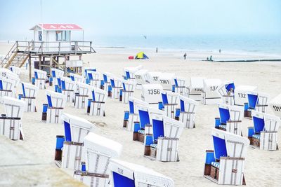 Hooded beach chairs on sand against sea