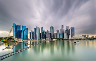 City at waterfront against cloudy sky