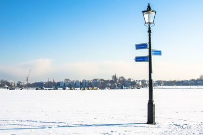 Street light on snow covered field against blue sky
